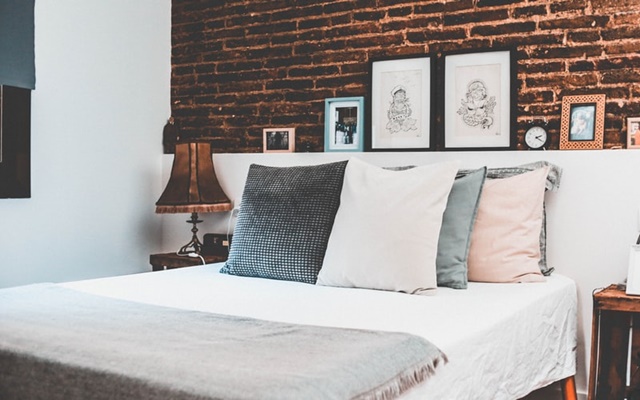 ruda chata-blog-funkcjonalna sypialnia-ergonomia w mieszkaniu-cegła w sypialni-poduszki-duże łóżko-plakaty